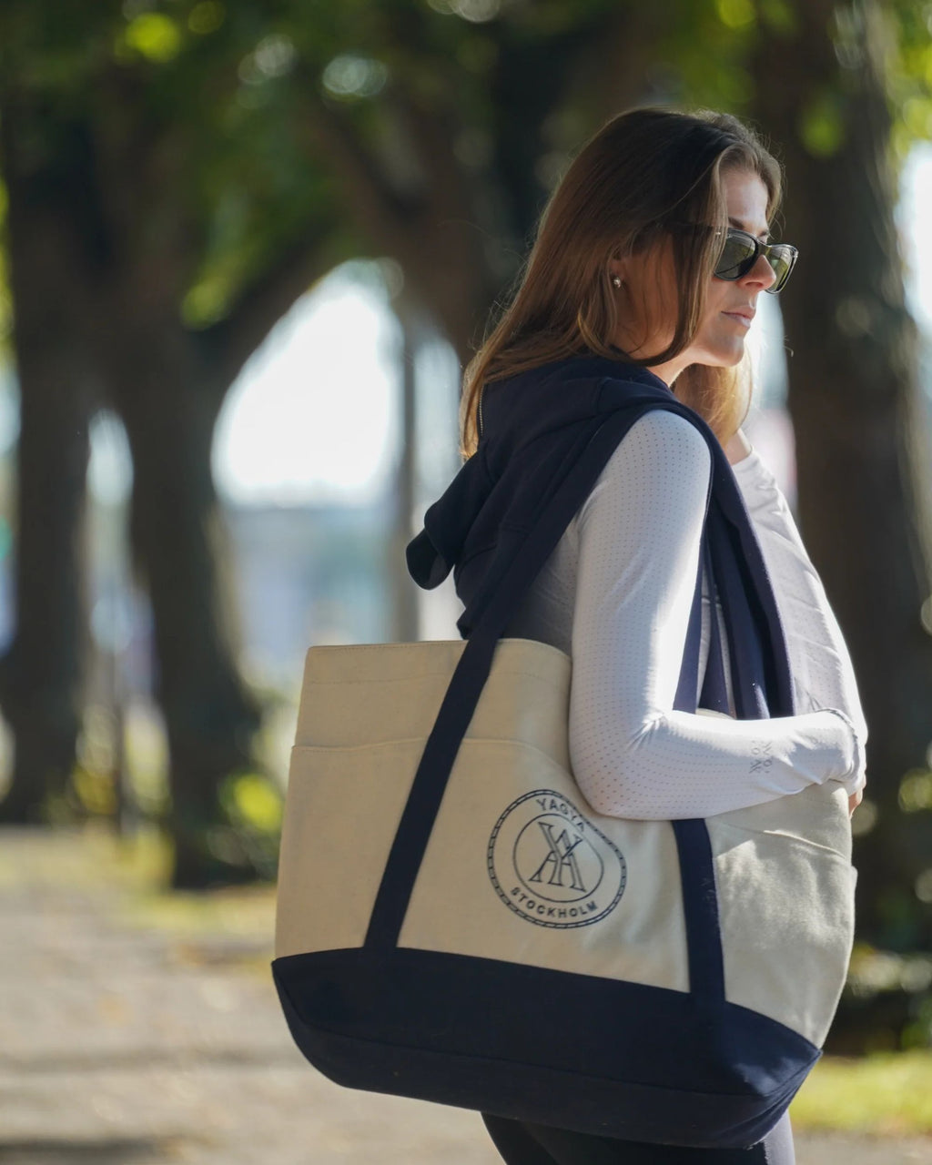 Woman walking outdoors with a tote bag featuring a logo