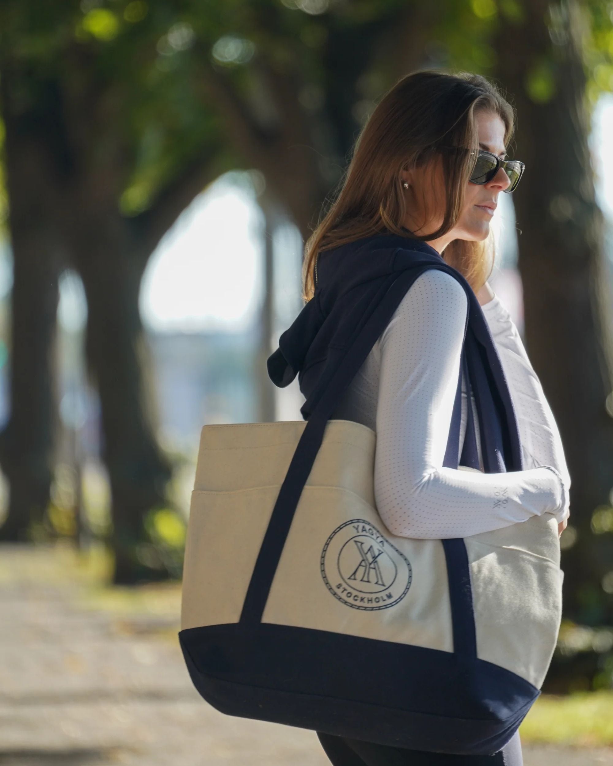 Woman walking outdoors with a tote bag featuring a logo